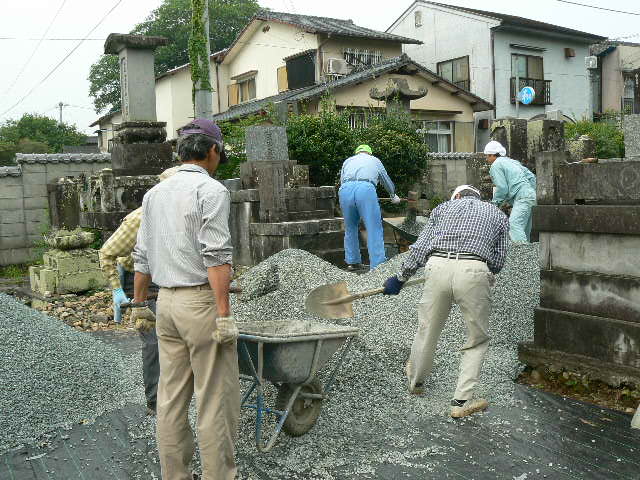 一輪車に砂利を積みこむ